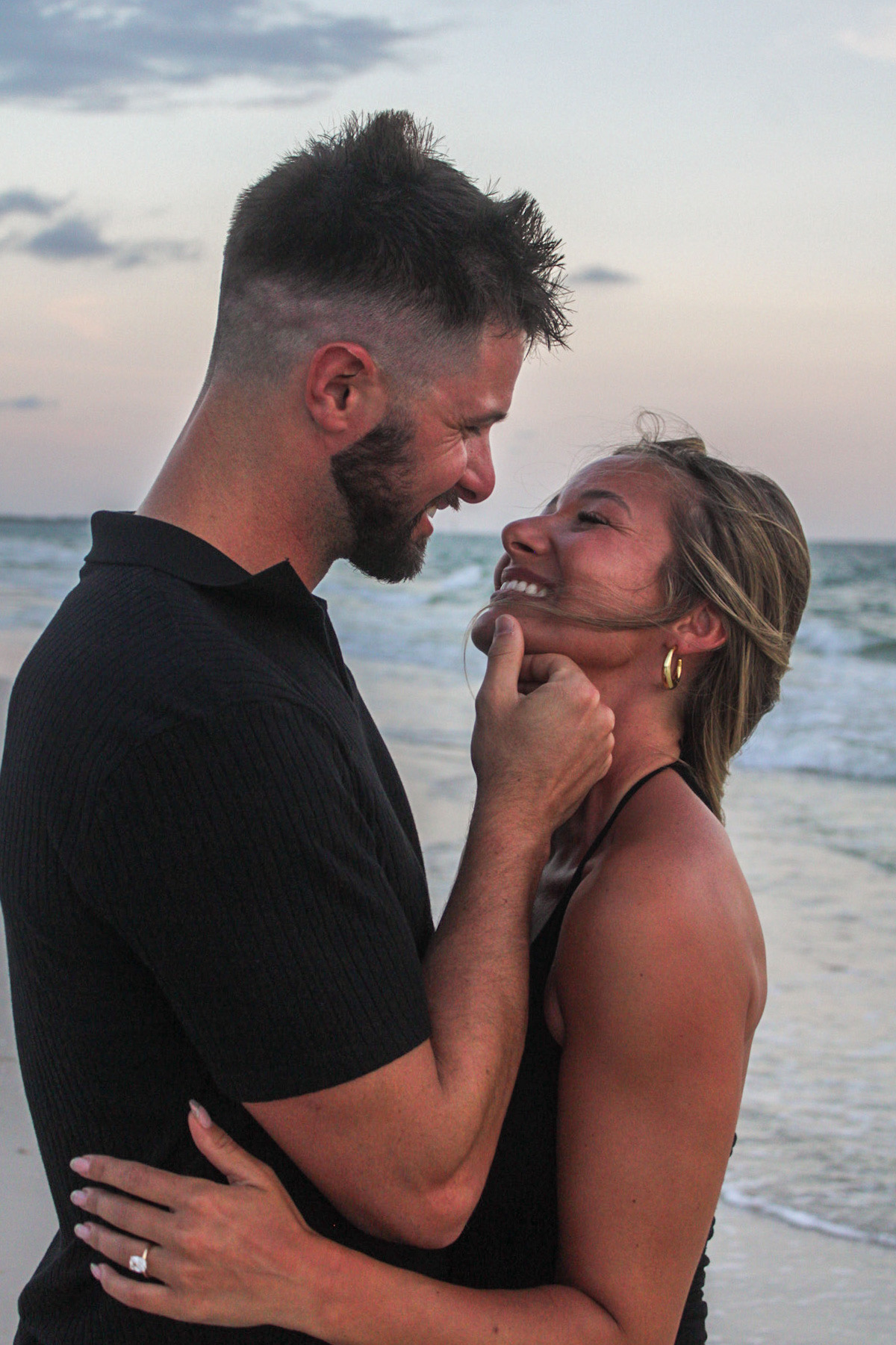 Couple smiling at each other beside the ocean by Miranda Rae Photography