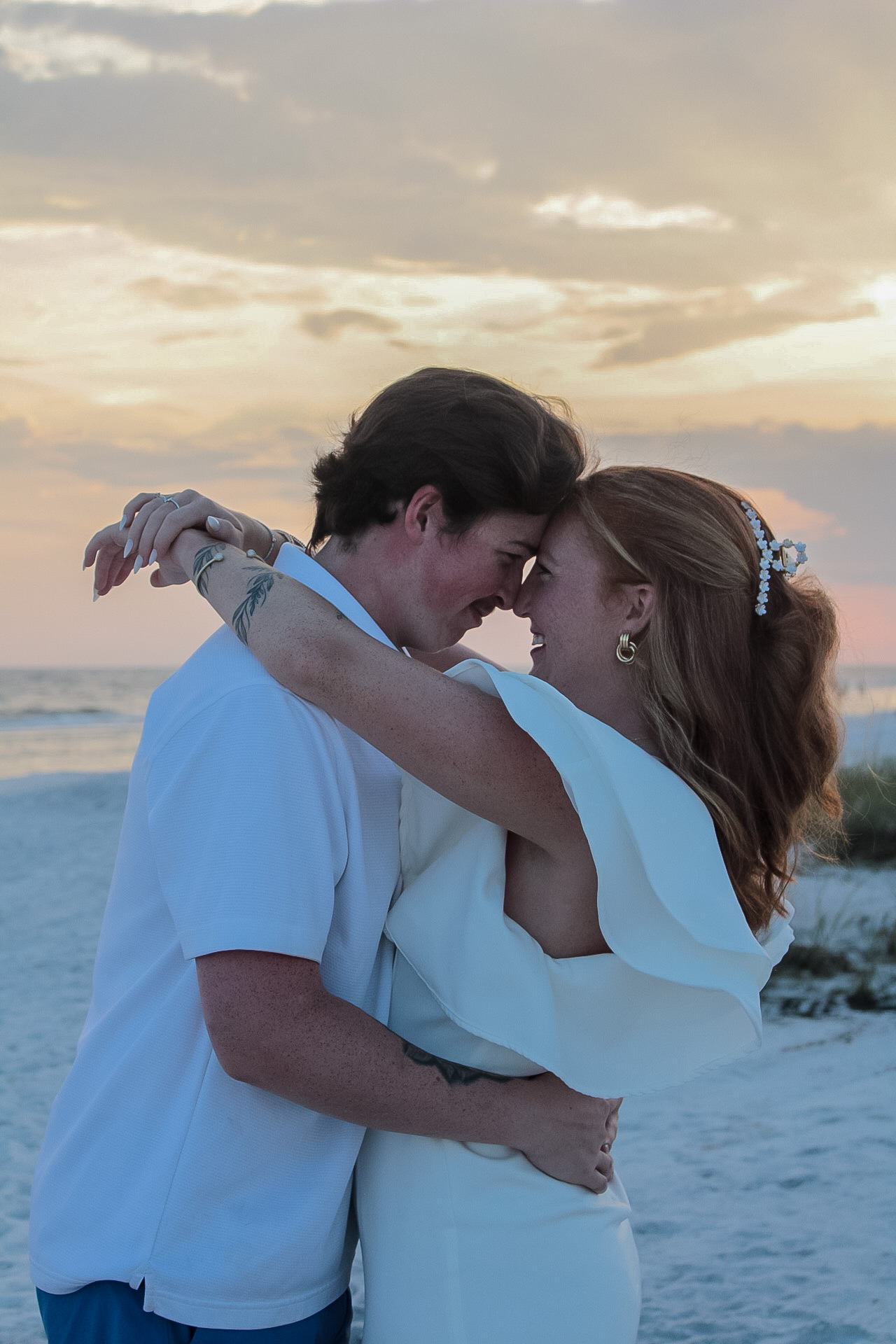 Couple dressed in white embracing on a Florida Gulf Coast beach at sunset